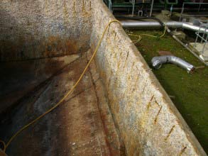 Barras de reforço fortemente corroídas e concreto danificado devido ao ataque químico em tanque de esgoto